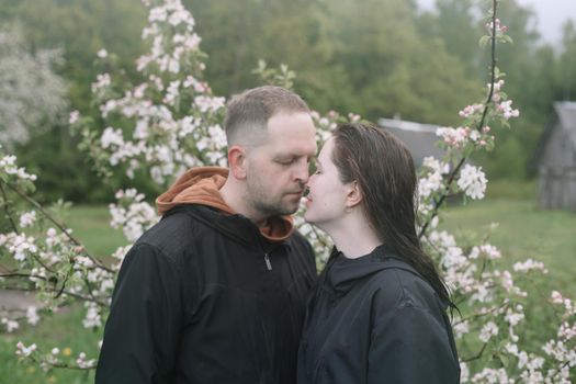 Sensual woman and man in cherry bloom. Couple in love in blossoming garden in spring. Love and romance, relationship, happy family outdoors.