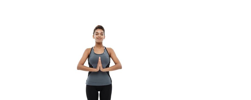 Healthy and Fitness concept - Beautiful American African lady in fitness clothing doing yoga and meditation. Isolated on white background