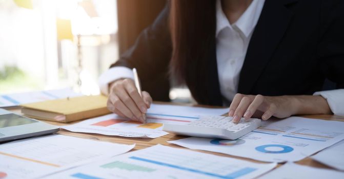 Close up of Hand business woman holding pen pointing on chart summary report and calculate finance..