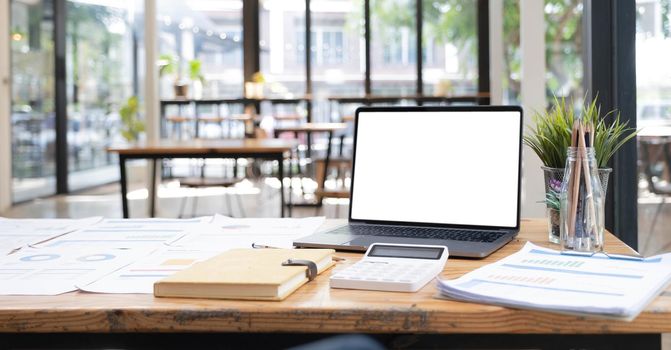 Laptop or notebook with blank screen on wood table in blurry background with house or office modern ,nature orange bokeh and sunlight in morning..