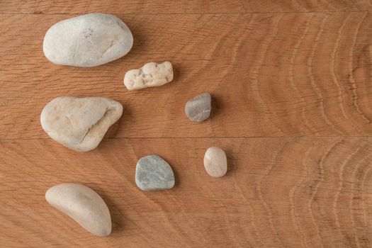 Smooth stones of various sizes are scattered on a wooden board