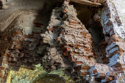 Destroyed wall of an ancient building built of red brick.