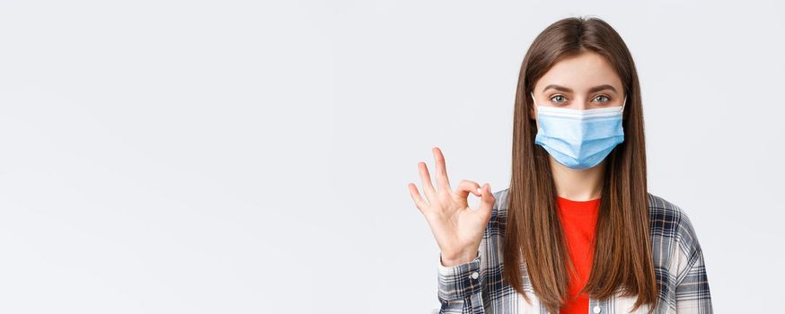 Coronavirus outbreak, leisure on quarantine, social distancing and emotions concept. Close-up of satisfied good-looking woman in medical mask, assure all good, show okay guarantee gesture.