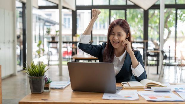 Portrait of happy young business asian woman celebrating success with arms up. positive expression, success in business concept