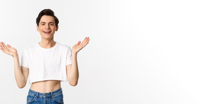 Lgbtq and pride concept. Happy and satisfied young gay man in crop top clapping hands proud, smiling at camera, standing over white background.