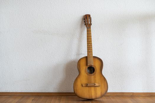classic guitar lying in front of a wall as background.