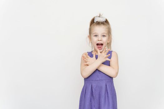 portrait of a little girl in a blue dress with a shocked expression on a light gray background. Wow offer concept.