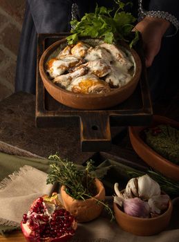 A vertical shot of a waitress presenting a chicken covered in a creamy sauce