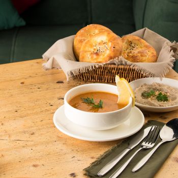 A closeup shot of a soup and appetizers near basket of breads