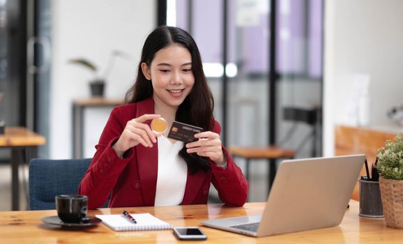 Pretty young Asian woman using laptop computer and using credit card for online shopping..