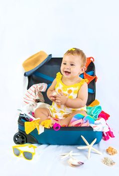 Baby is sitting in a suitcase, getting ready for a travel. Selective focus. Child.