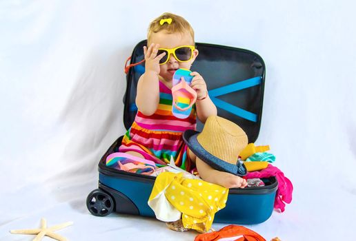 Baby is sitting in a suitcase, getting ready for a travel. Selective focus. Child.