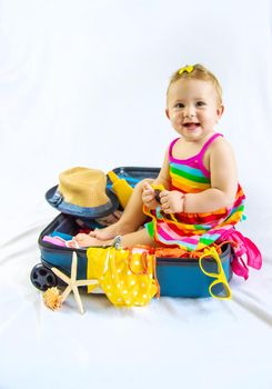 Baby is sitting in a suitcase, getting ready for a travel. Selective focus. Child.
