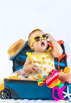 Baby is sitting in a suitcase, getting ready for a travel. Selective focus. Child.