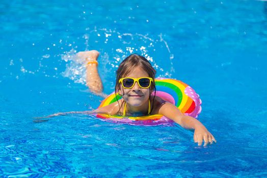 The child swims with a circle in the pool. Selective focus. Kid.