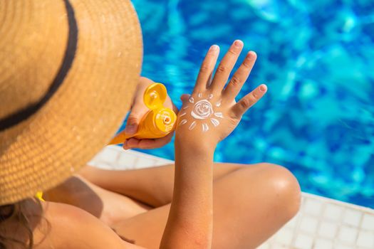 The child smears sunscreen on her hand. Selective focus. Kid.