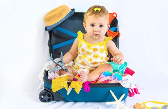 Baby is sitting in a suitcase, getting ready for a travel. Selective focus. Child.
