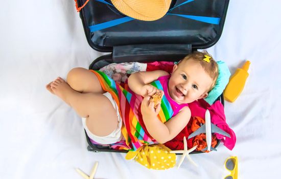 Baby is sitting in a suitcase, getting ready for a travel. Selective focus. Child.