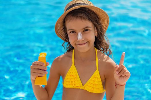 The child is putting sunscreen on her face. Selective focus. Kid.