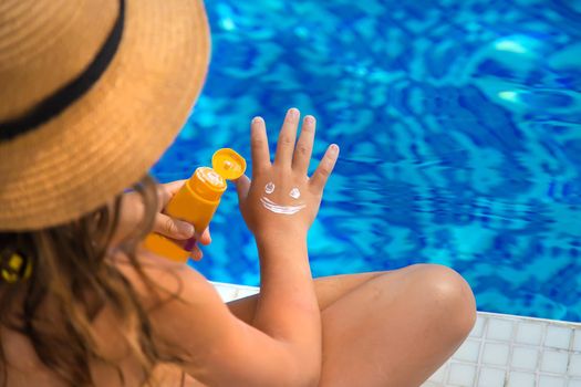 The child smears sunscreen on her hand. Selective focus. Kid.