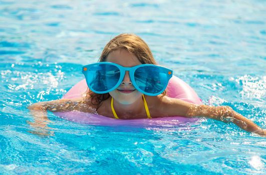 The child is swimming in the pool. Selective focus. Kid.