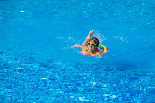 The child swims with a circle in the pool. Selective focus. Kid.