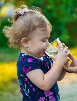 The child drinks water from a glass. Selective focus. Kid.