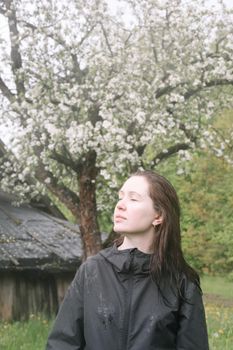 emotional portrait of a young woman standing alone under rain outdoors in spring