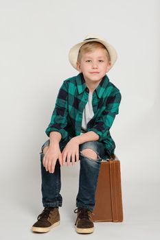 Portrait of cute stylish blond boy kid 7 years old wearing hat and checked shirt and jeans