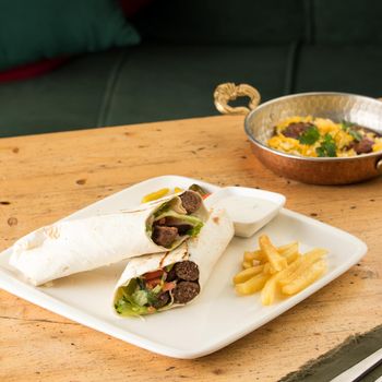 A closeup shot of kebabs with vegetables wrapped in a tortilla