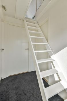 A simple minimalist room with a white staircase to the attic and a stylish carpet