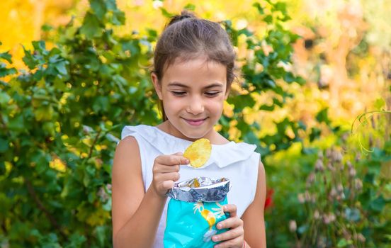 The child is eating chips. Selective focus. Kid.