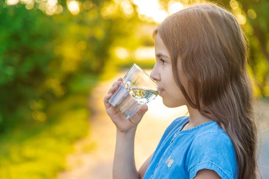 The child drinks water from a glass. Selective focus. Kid.