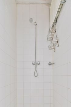 Interior of narrow bathroom and toilet with showroom, sink and wall hung toilet with white walls and checkered floor