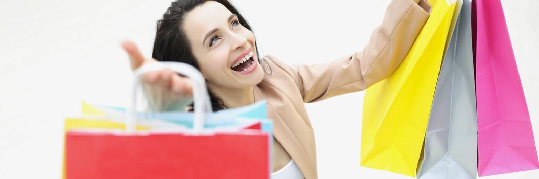 Portrait of young woman shopaholic laughing and being happy about bought things. Girl carry many packs with clothes. Big sale, shopping, discount concept