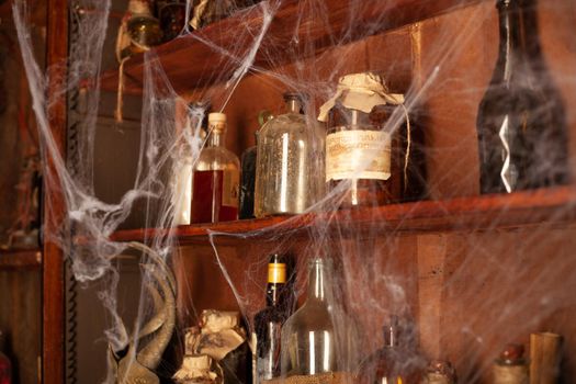 Halloween background Shelves with alchemy tools Skull spiderweb bottle with poison candles Witcher workspace Scarry room