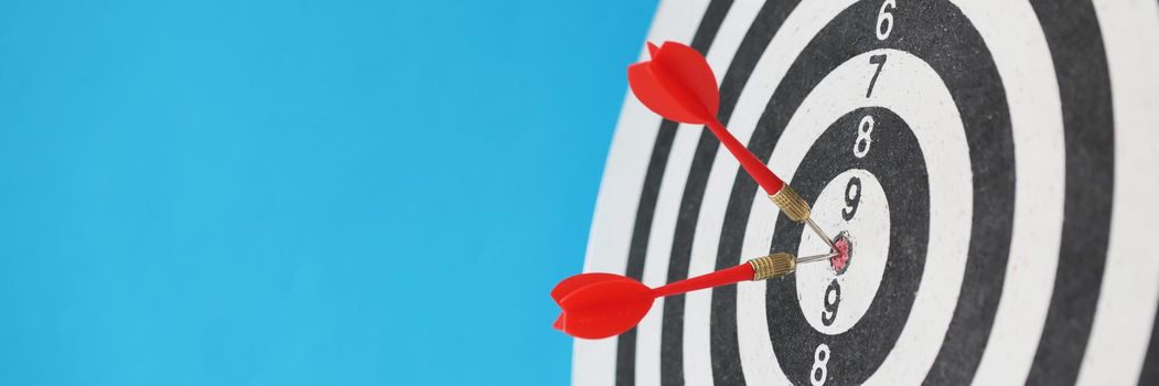 Close-up of two red dart arrows hitting in target center of round dartboard. Business targeting, winning goals and developing strategy concept. Copy space