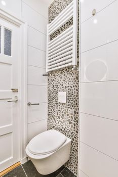 Interior of narrow restroom with wall hung toilet with white walls and checkered floor