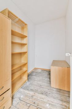 cupboard and vintage chest placed near doors and wicker basket in spacious room with white walls and wooden floor