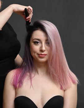 Hairdresser's hands combing the dyed hair of a pretty model