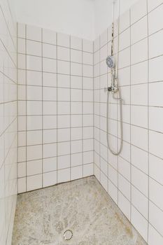 Bathtub with glass shower placed in corner near sink with white tile walls