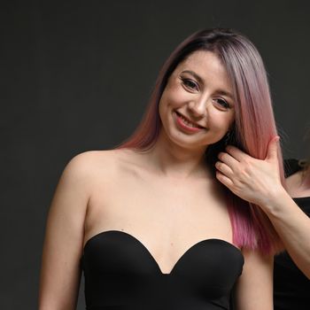 Portrait of a smiling model with dyed hair in the hairdresser's hand