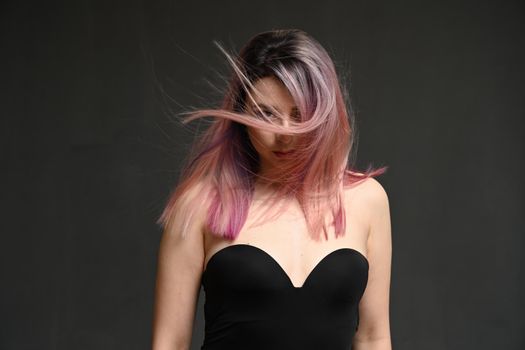 Model's hair blowing in the wind. Portrait on a gray background