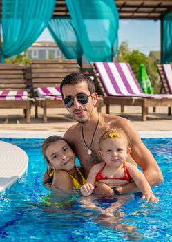 Father with daughters in the pool. Selective focus. Child.