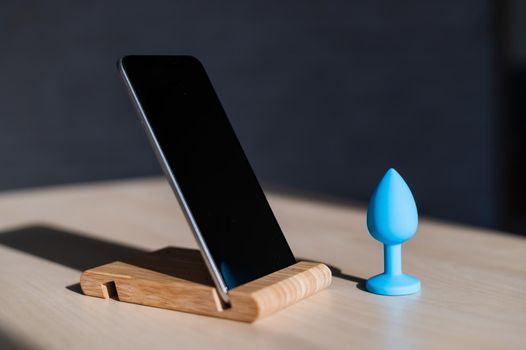 Blue anal plug synchronizing with a smartphone. Latex vibrator delivering for carnal pleasures