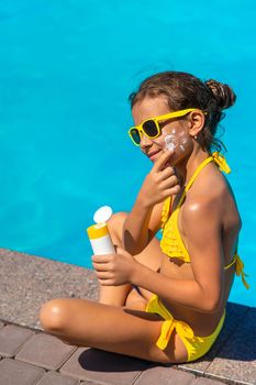 Sunscreen near the pool on the face of the child. Selective focus. Kid.