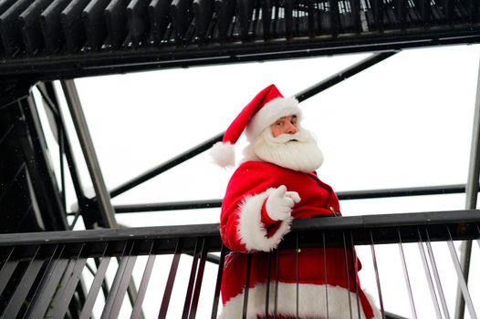 Santa claus looks down from the stairs and wishes a merry christmas outdoors.