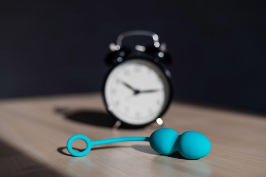 Alarm clock and vibrator on the table. Time for training intimate muscles. Vaginal balls strengthen the pelvic floor muscles for powerful orgasms