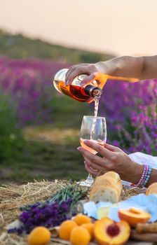 A woman holds wine in glasses. Picnic in the lavender field. Selective focus. nature.