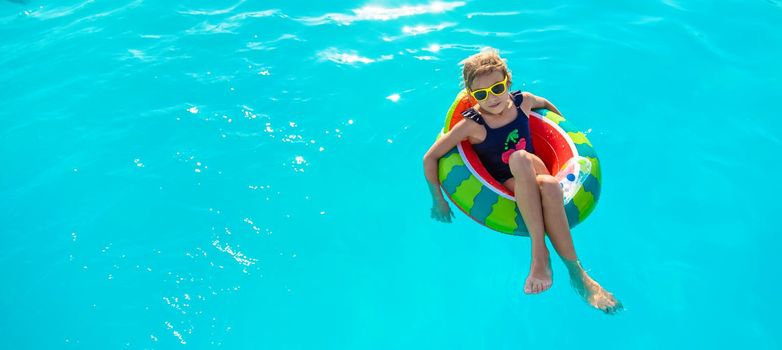 A child in a circle swims in the pool. Selective focus. Kid.